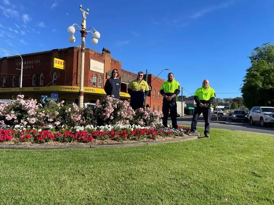 A group of people standing in front of a flower bed  AI-generated content may be incorrect.